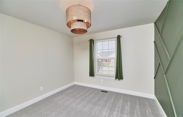 unfurnished room featuring baseboards, visible vents, a chandelier, and carpet flooring