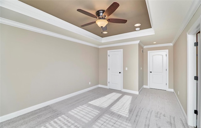 spare room with recessed lighting, light carpet, baseboards, ornamental molding, and a raised ceiling