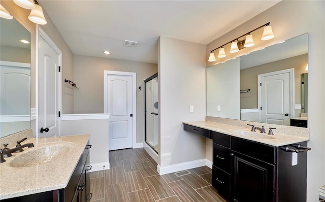 bathroom featuring a stall shower, visible vents, a sink, and baseboards