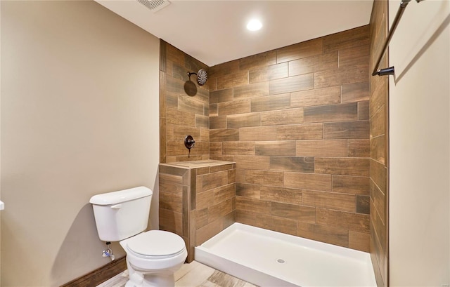 bathroom with toilet, visible vents, and tiled shower