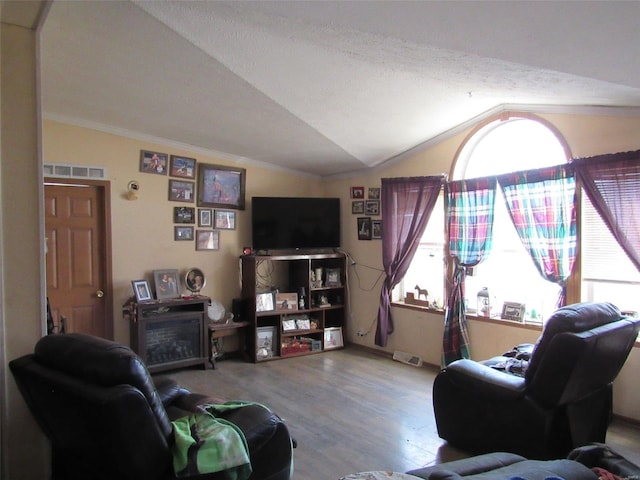 living area featuring visible vents, ornamental molding, vaulted ceiling, and wood finished floors