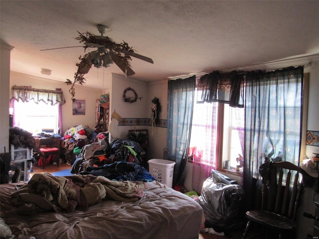 bedroom with a textured ceiling, ornamental molding, and a ceiling fan