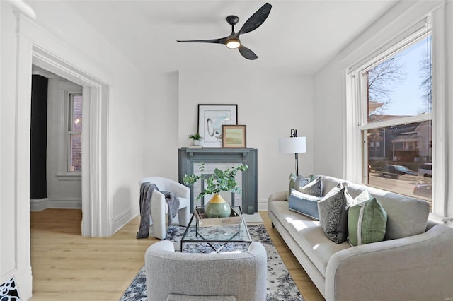 living area featuring baseboards, a ceiling fan, and wood finished floors