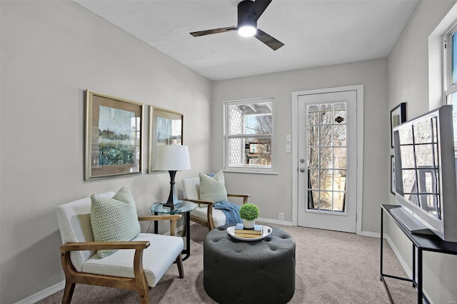 living area with a ceiling fan, carpet, a textured ceiling, and baseboards