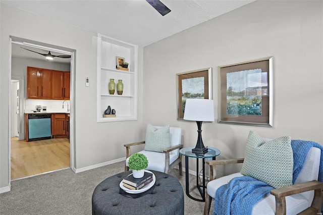 sitting room featuring built in shelves, light colored carpet, and baseboards