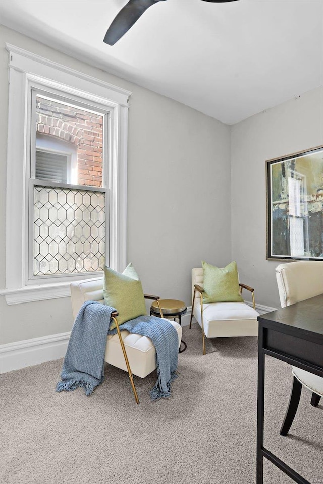 living area featuring ceiling fan, plenty of natural light, carpet flooring, and baseboards