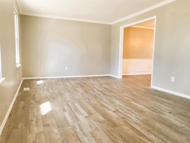 unfurnished room with ornamental molding, light wood-type flooring, visible vents, and a decorative wall