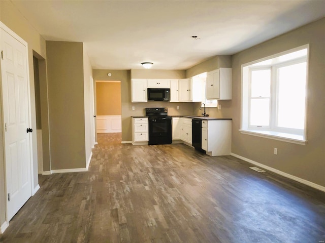 kitchen featuring black appliances, a sink, dark wood finished floors, and white cabinets