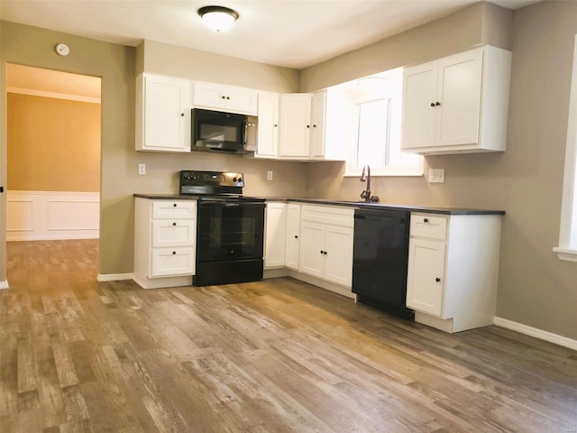 kitchen with dark countertops, black appliances, and white cabinets