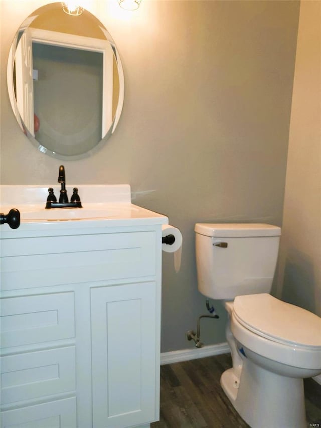 bathroom featuring baseboards, vanity, toilet, and wood finished floors