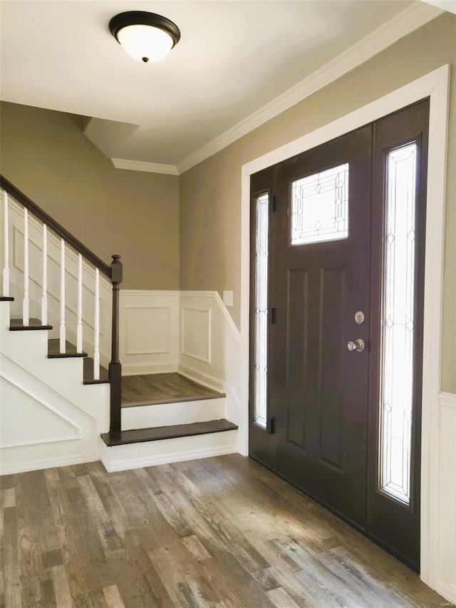 foyer entrance featuring stairway, wainscoting, wood finished floors, and crown molding