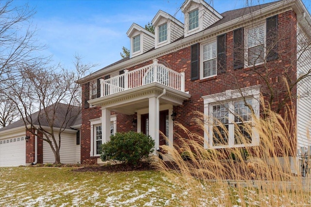 view of front of home featuring brick siding, an attached garage, and a balcony