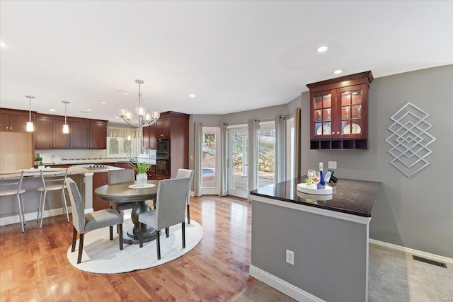 dining room with light wood-style flooring, visible vents, a chandelier, and baseboards