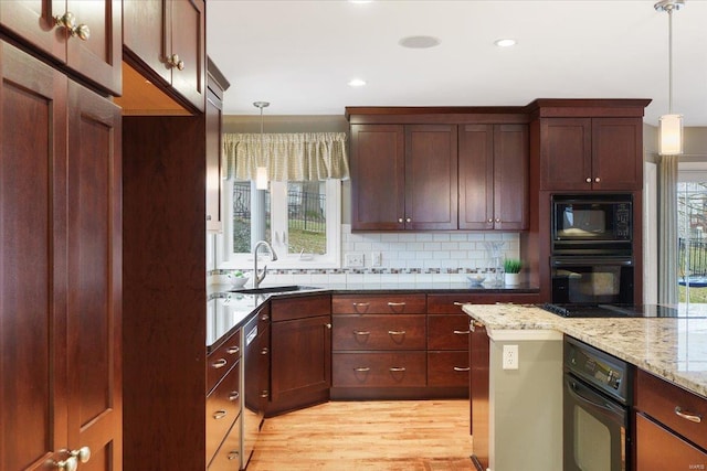 kitchen with tasteful backsplash, decorative light fixtures, a sink, and black appliances