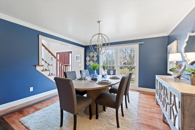 dining space with ornamental molding, a notable chandelier, light wood-style floors, and baseboards