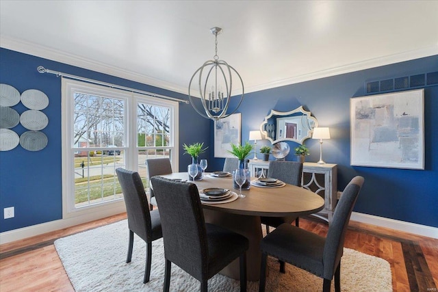 dining room with a notable chandelier, wood finished floors, visible vents, baseboards, and ornamental molding