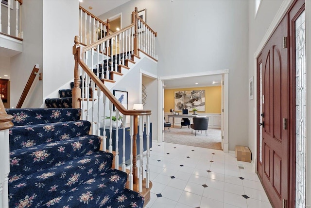 tiled entryway featuring stairs and a high ceiling