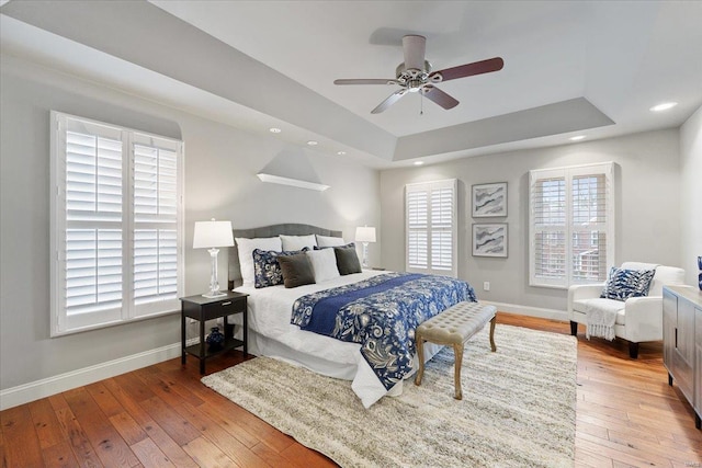 bedroom with recessed lighting, a raised ceiling, baseboards, and hardwood / wood-style floors