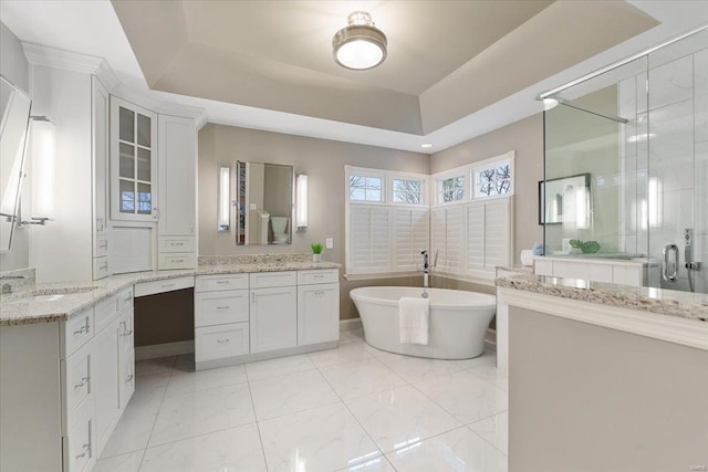 full bath featuring a soaking tub, a sink, a tray ceiling, a shower stall, and two vanities