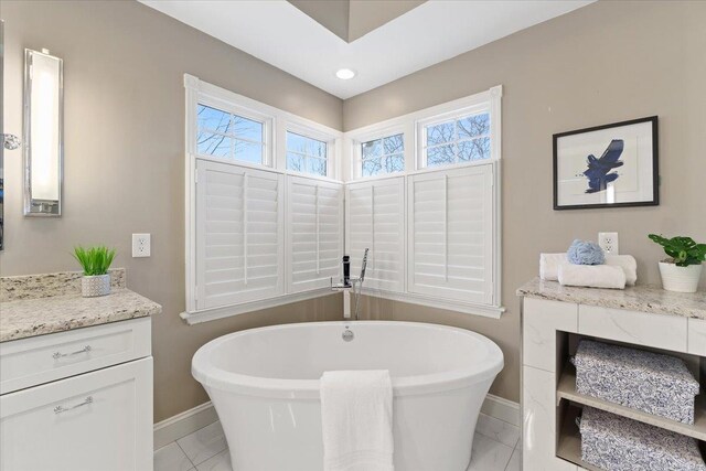 full bath featuring a soaking tub, baseboards, marble finish floor, and vanity