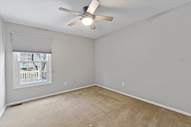 carpeted spare room featuring visible vents, ceiling fan, and baseboards