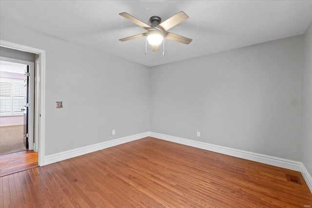 unfurnished room featuring baseboards, visible vents, ceiling fan, and wood finished floors