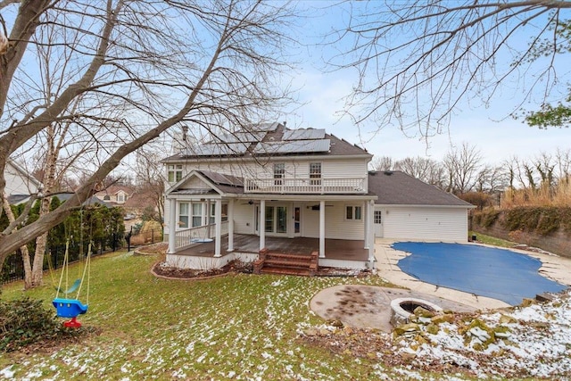 view of front of house with french doors, roof mounted solar panels, a covered pool, a front lawn, and a patio area