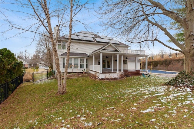 exterior space featuring a fenced backyard, solar panels, a ceiling fan, a lawn, and a chimney