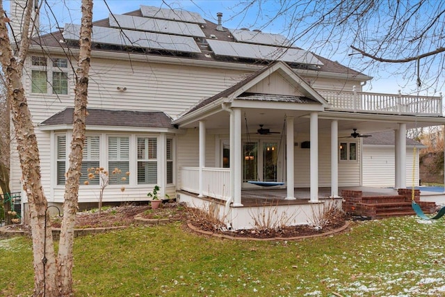 view of front of property featuring covered porch, ceiling fan, a front lawn, and solar panels