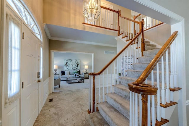 entryway with a high ceiling, visible vents, and crown molding