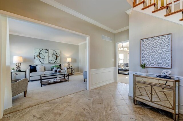 carpeted living room with a wainscoted wall, visible vents, a decorative wall, an inviting chandelier, and ornamental molding