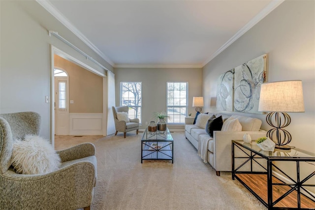 carpeted living room with ornamental molding, a wainscoted wall, and a decorative wall