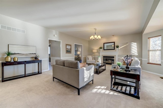 living room with a chandelier, visible vents, baseboards, carpet, and a glass covered fireplace