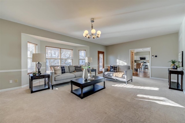 living room with carpet flooring, baseboards, and an inviting chandelier