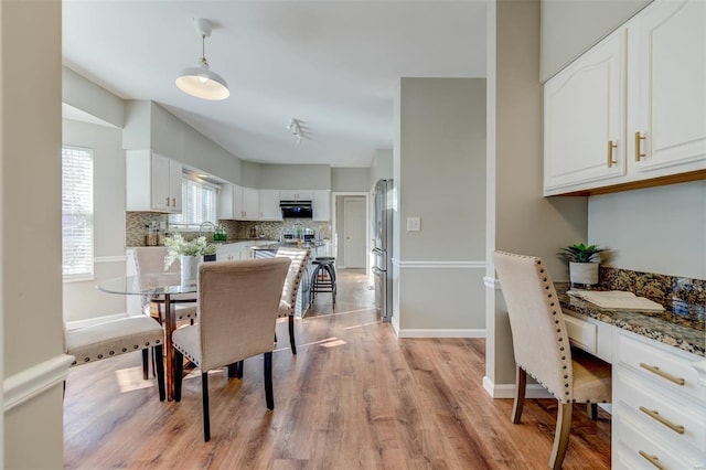 dining area featuring light wood-type flooring, built in study area, and baseboards