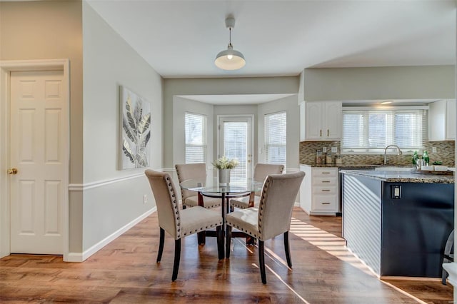 dining room featuring a healthy amount of sunlight, baseboards, and wood finished floors