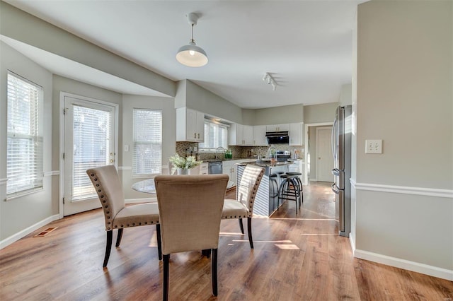 dining room with light wood-type flooring, visible vents, and baseboards