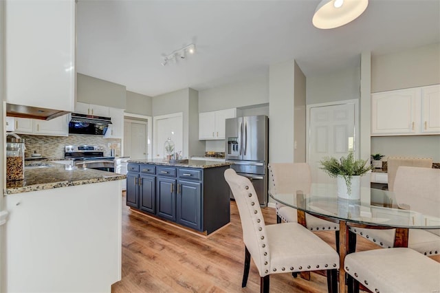 kitchen featuring light wood finished floors, white cabinets, appliances with stainless steel finishes, blue cabinets, and backsplash