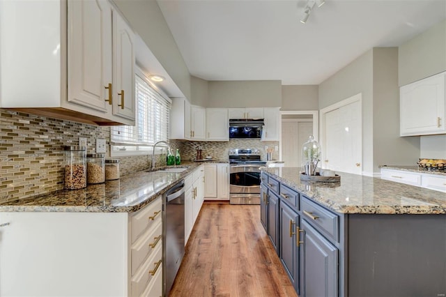 kitchen featuring stainless steel appliances, backsplash, white cabinetry, and a center island