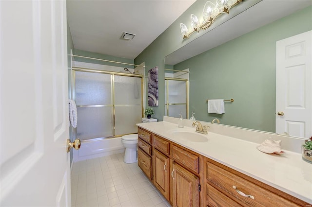 bathroom featuring visible vents, toilet, combined bath / shower with glass door, vanity, and tile patterned flooring