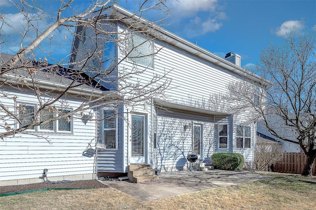 back of house with entry steps, fence, and a chimney