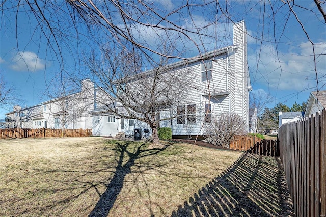 rear view of property with a yard, a chimney, and a fenced backyard