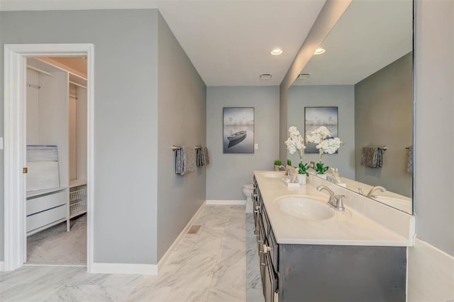 full bathroom with marble finish floor, a sink, baseboards, and double vanity