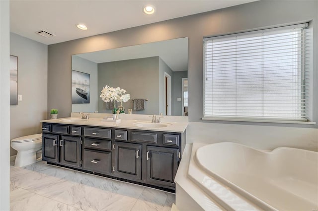 full bathroom with double vanity, visible vents, a tub, marble finish floor, and a sink