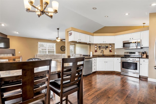 kitchen with dark countertops, dark wood-style floors, appliances with stainless steel finishes, vaulted ceiling, and a sink