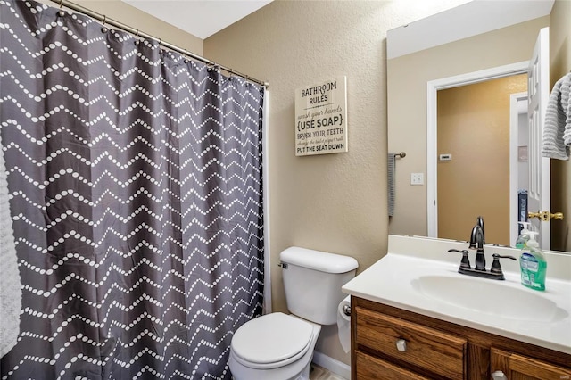 bathroom featuring a textured wall, a shower with shower curtain, vanity, and toilet