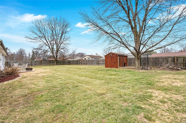 view of yard with a storage shed, an outdoor fire pit, an outbuilding, and a fenced backyard