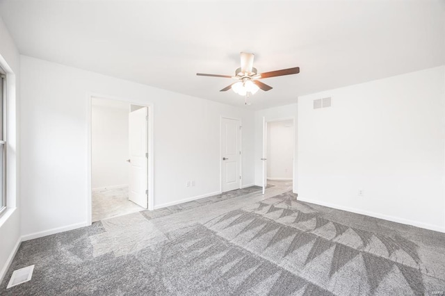 carpeted spare room with visible vents, baseboards, and a ceiling fan