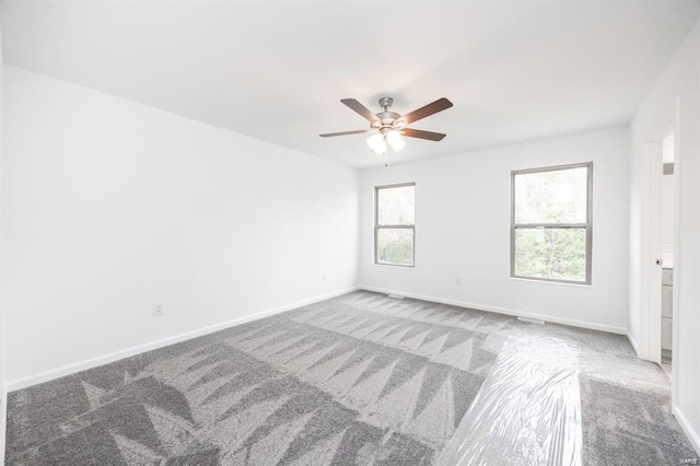 carpeted empty room featuring a ceiling fan and baseboards