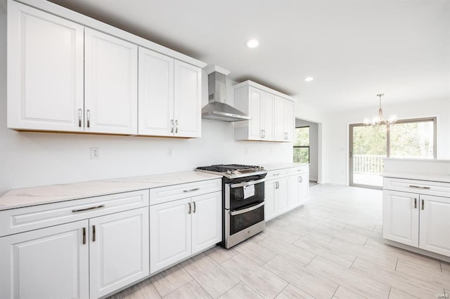 kitchen with decorative light fixtures, double oven range, recessed lighting, white cabinets, and wall chimney range hood